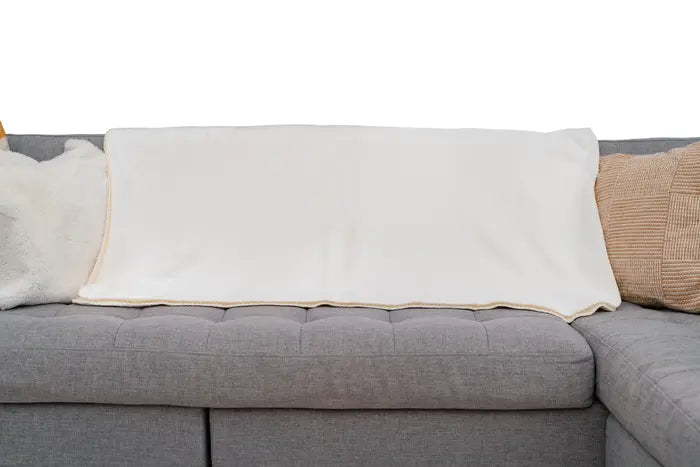 White blanket draped over a gray sofa with cushions.