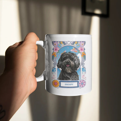 Person holding a mug with a dog illustration and 'Snoopy' text in a floral frame.